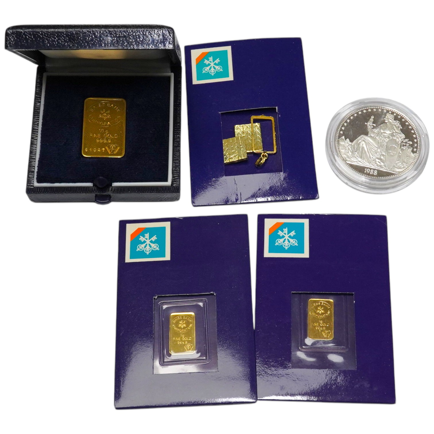 Three small 'gold Fine .999' bullion ingots, (two 1g and one 10g), two yellow metal segments and a 1oz silver coin. Condition - fair to good